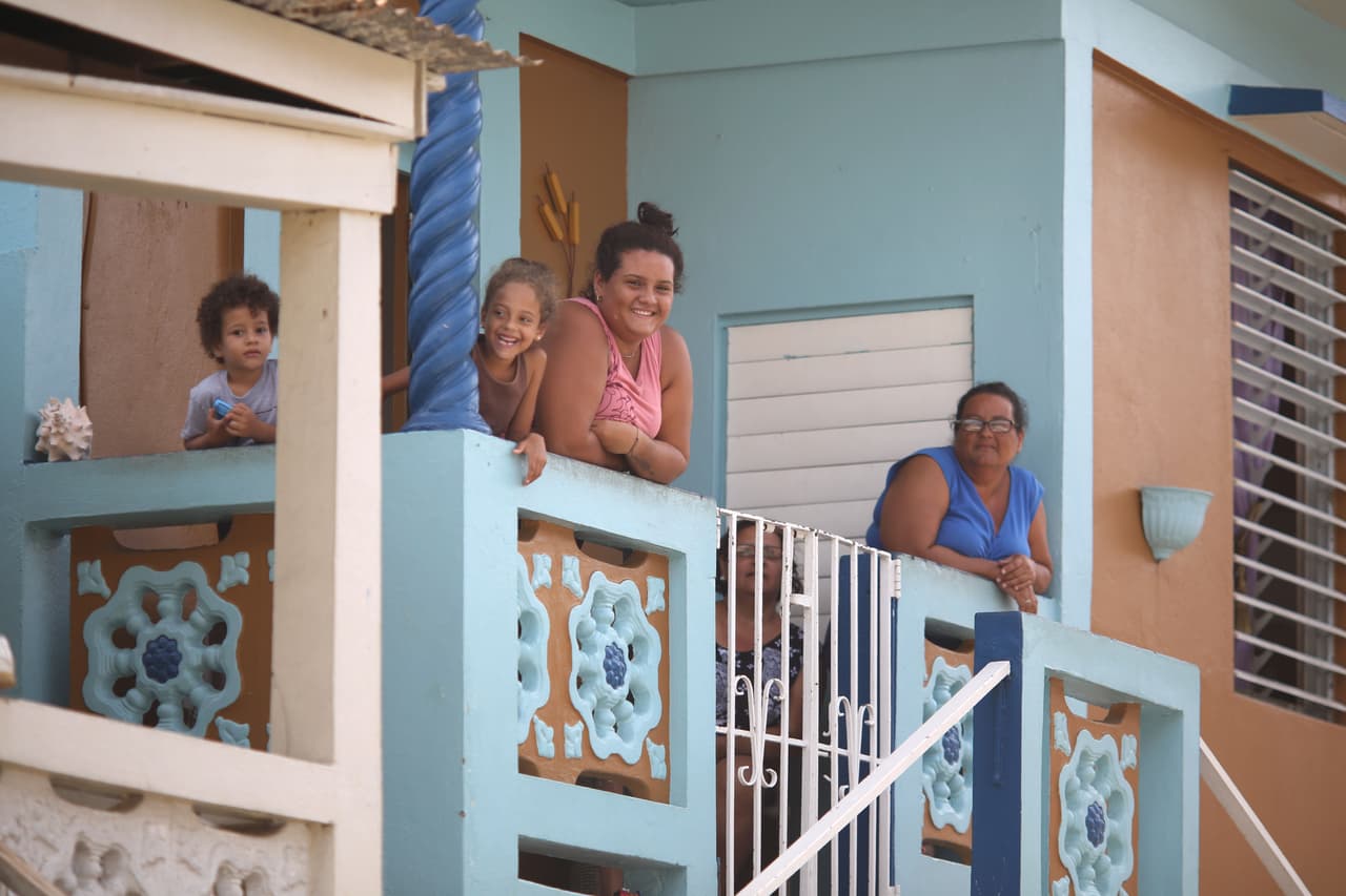 La familia Cote Plaza mira la destrucción de su pueblo desde un balcón de su casa en Judea, Utuado.