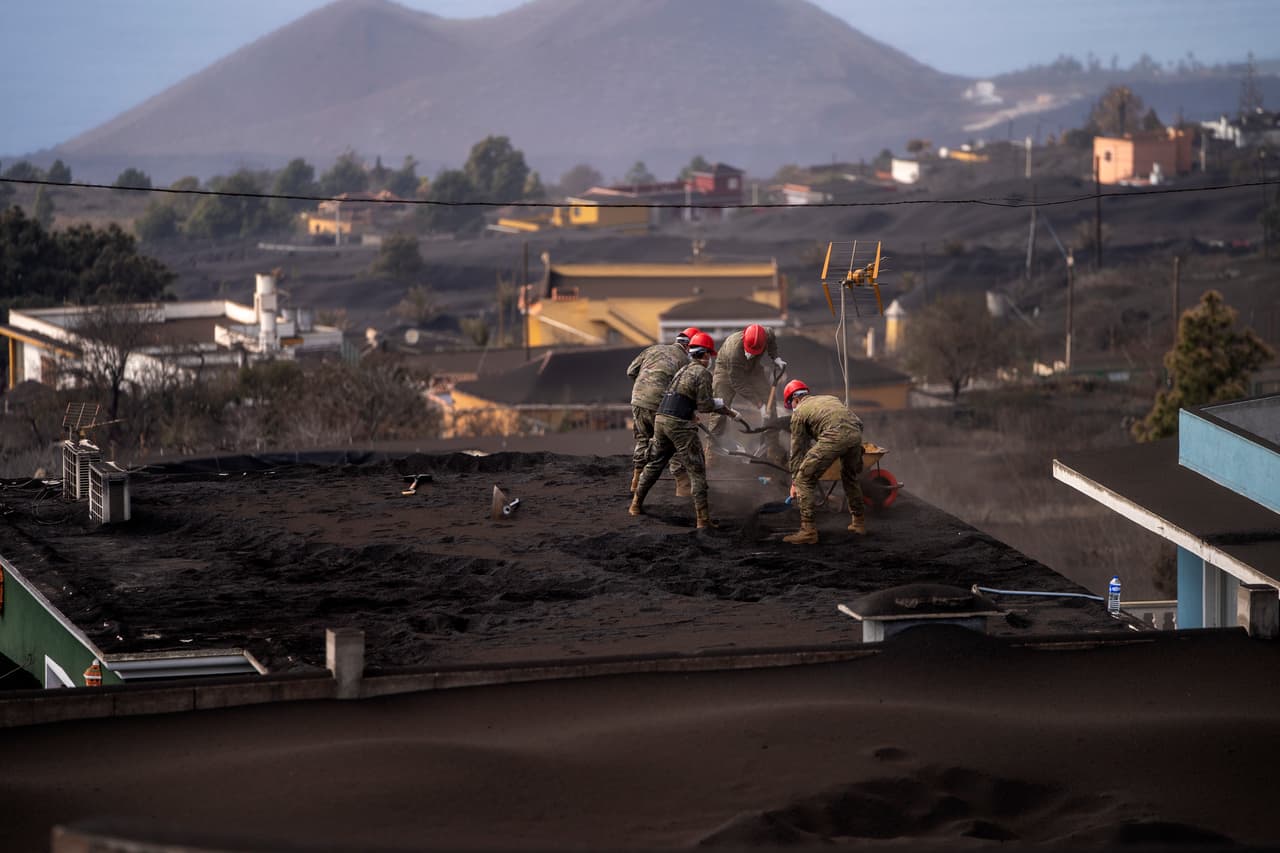 Soldados retiran la ceniza del techo de una casa en la isla de La Palma. Pese a la emergencia, las autoridades
<b>calculan que unas 10,000 personas acudirán a la isla este fin de semana</b> y reportaron que los hoteles tienen un 90% de ocupación.