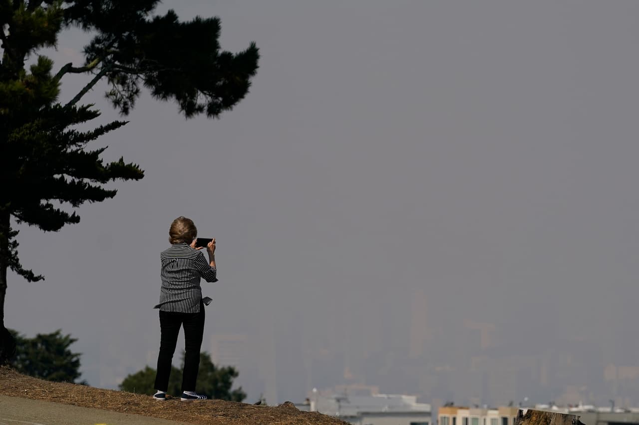 La estela de humo ha llegado hasta Baja California, en México, y a los estados de Oregón, Montana, Idaho, Utah, Colorado y Wyoming. En la imagen, una mujer toma una fotogafía desde una de las colinas que suelen ofrecer una vista panorámica de San Francisco.