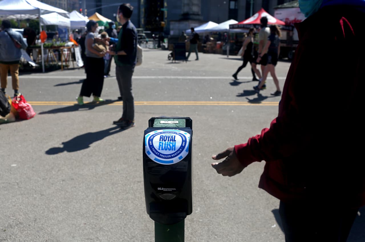 Uno de los visitantes del mercado que se instala los fines de semana en Pospect Park usa uno de los desinfectantes de manos instalados en el lugar. El gobernador del estado de Nueva York, Andrew Cuomo, indicó que considerará reducir los requisitos de cierre en regiones del estado a partir del 15 de mayo.