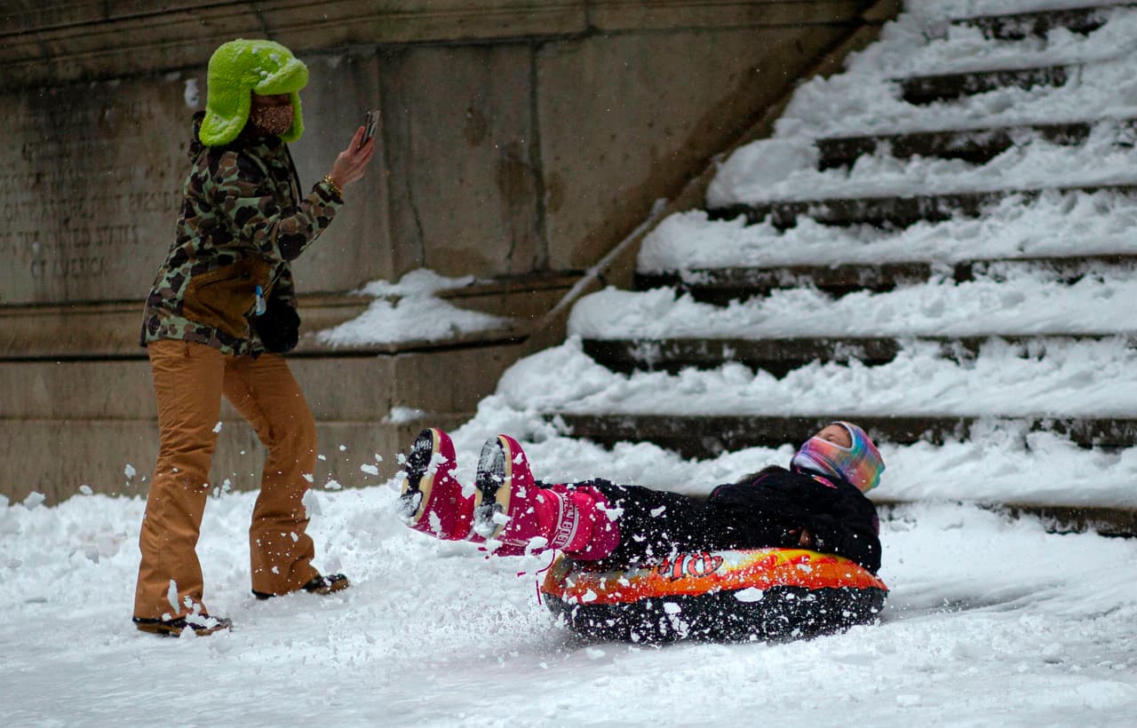 La gente juega mientras cae la nieve en Wall Street durante la nevada