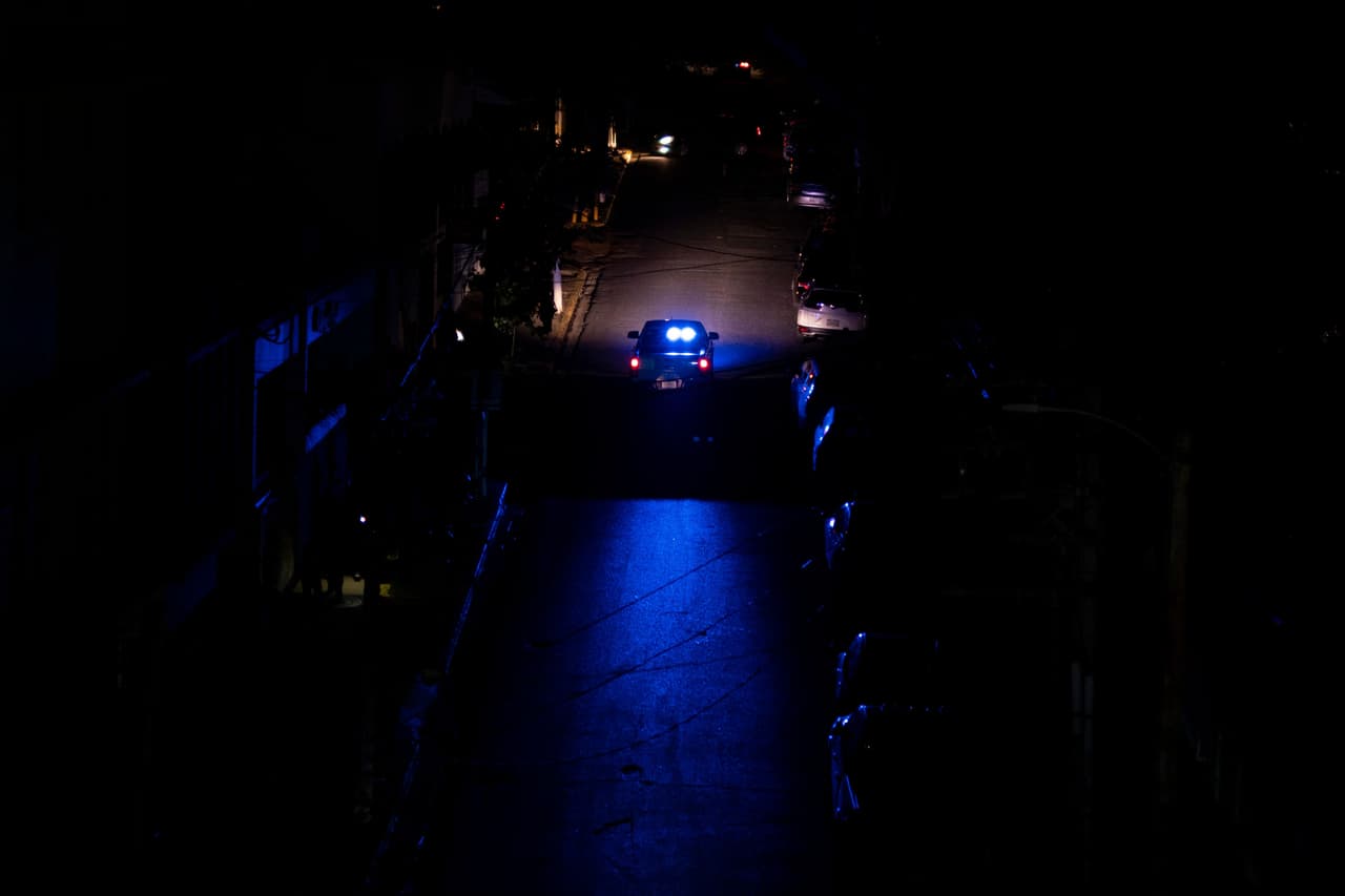 Un coche de policía patrulla una calle oscura en San Juan, Puerto Rico, mientras a miles de clientes de LUMA Energy se quedaron sin luz.