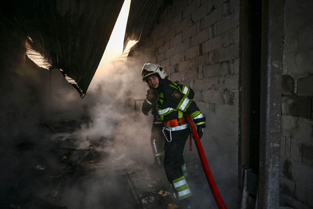 Un bombero extingue un incendio en una casa golpeada por las tropas rusas en Kiev, que han podido apostarse en los alrededores de la capital este sábado. En otras ciudades, como Mariupol, mantienen su bloqueo mientras crece la crisis humanitaria por las miles de personas que no lograron salir.