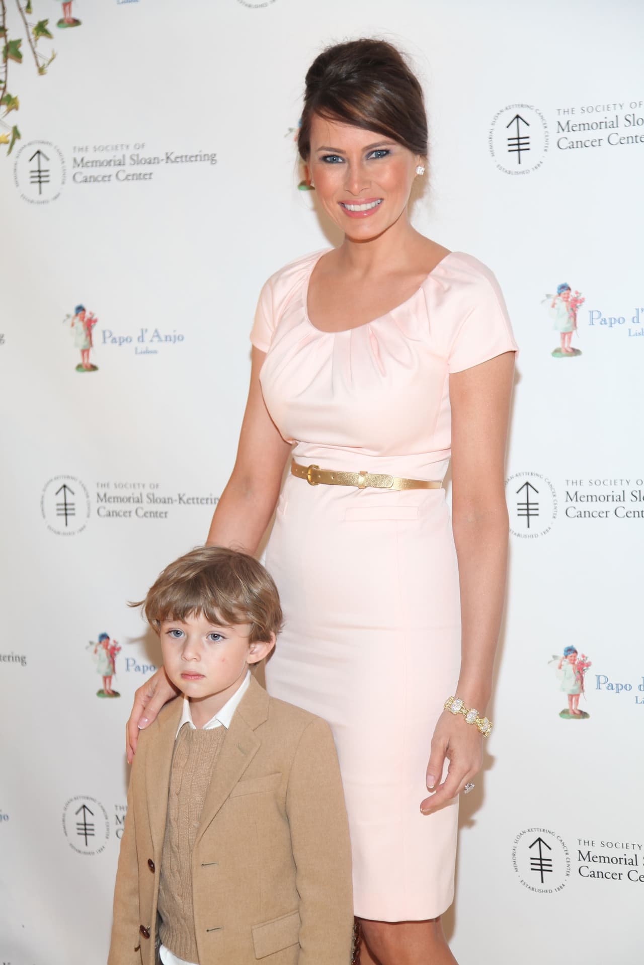 Melania Trump con su hijo Barron en la cena de beneficencia de 'Bunny Hop' en 2009, con un vestido rosa que accesorizó con un cinturón dorado y unas perlas.