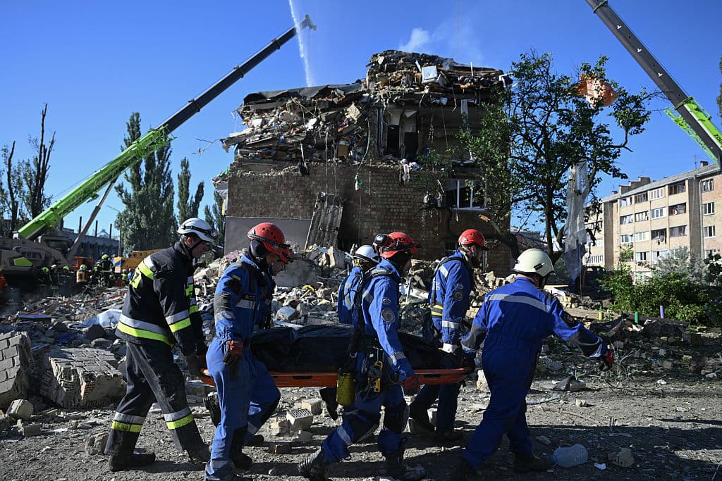 Rescatistas ucranianos transportan el cuerpo de una víctima recuperado durante una operación de búsqueda y rescate en un edificio residencial gravemente dañado tras un ataque con misiles rusos en Kiev el 28 de agosto de 2025.