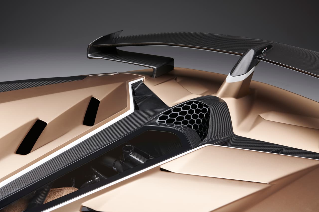 En su parte posterior, lo primero que destaca es el enorme cobertor para el motor fabricado en un compuesto de carbono. Este material no solo reduce el peso, sino que permite la fabricación de esta pieza TAN compleja. Sobre ella vemos 4 extractores rectangulares en los flancos del polímero transparente que permite apreciar solo una parte del motor.