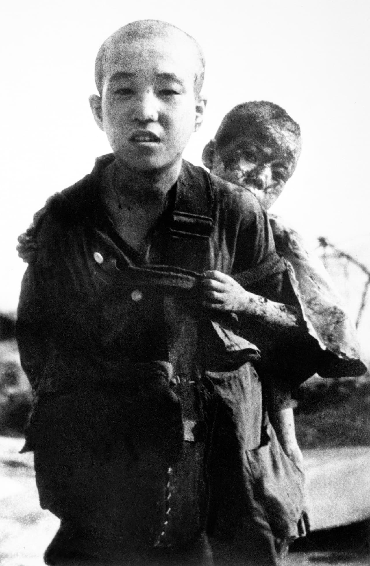 Un niño no identificado lleva a su hermano quemado en su espalda, el 10 de agosto de 1945 en Nagasaki. Estas fotografías no fueron divulgadas al público por el ejército japonés pero fueron difundidas a la prensa mundial por las Naciones Unidas después de la guerra.