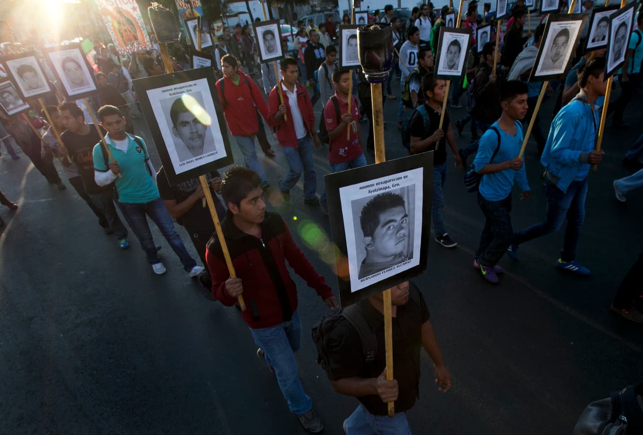 ARCHIVO - En esta foto de archivo del 26 de diciembre de 2015, familiares de los 43 estudiantes desaparecidos de Ayotzinapa marchan con fotos por la Ciudad de México. Un grupo de forenses argentinos dijo el martes 9 de febrero de 2016 que ha determinado que no hay pruebas biológicas o físicas de que los 43 estudiantes desaparecidos en el sur de México en 2014 fueron incinerados en un basurero, como sostuvo inicialmente el gobierno. (AP Foto/Marco Ugarte, File)
