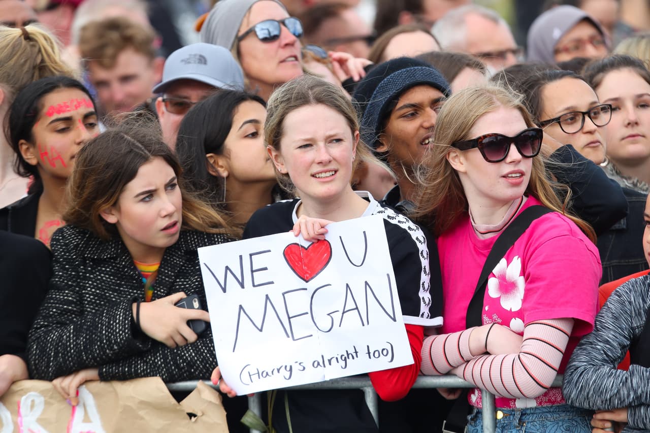 Entre los asistentes llamó la atención esta joven que llevaba un letrero con la frase "te amamos, Meghan' y una pequeña referencia al esposo de la duquesa: 'Harry está bien también'.