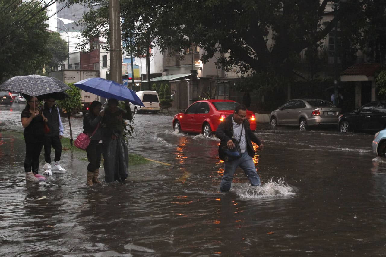 Un hombre intenta cruzar una calle inundada.