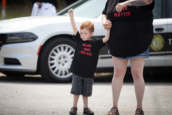 Un niño levanta el puño. En su camisa se lee el lema "Black Lives Matter" que puede traducirse como "Las Vidas Negras Importan".
