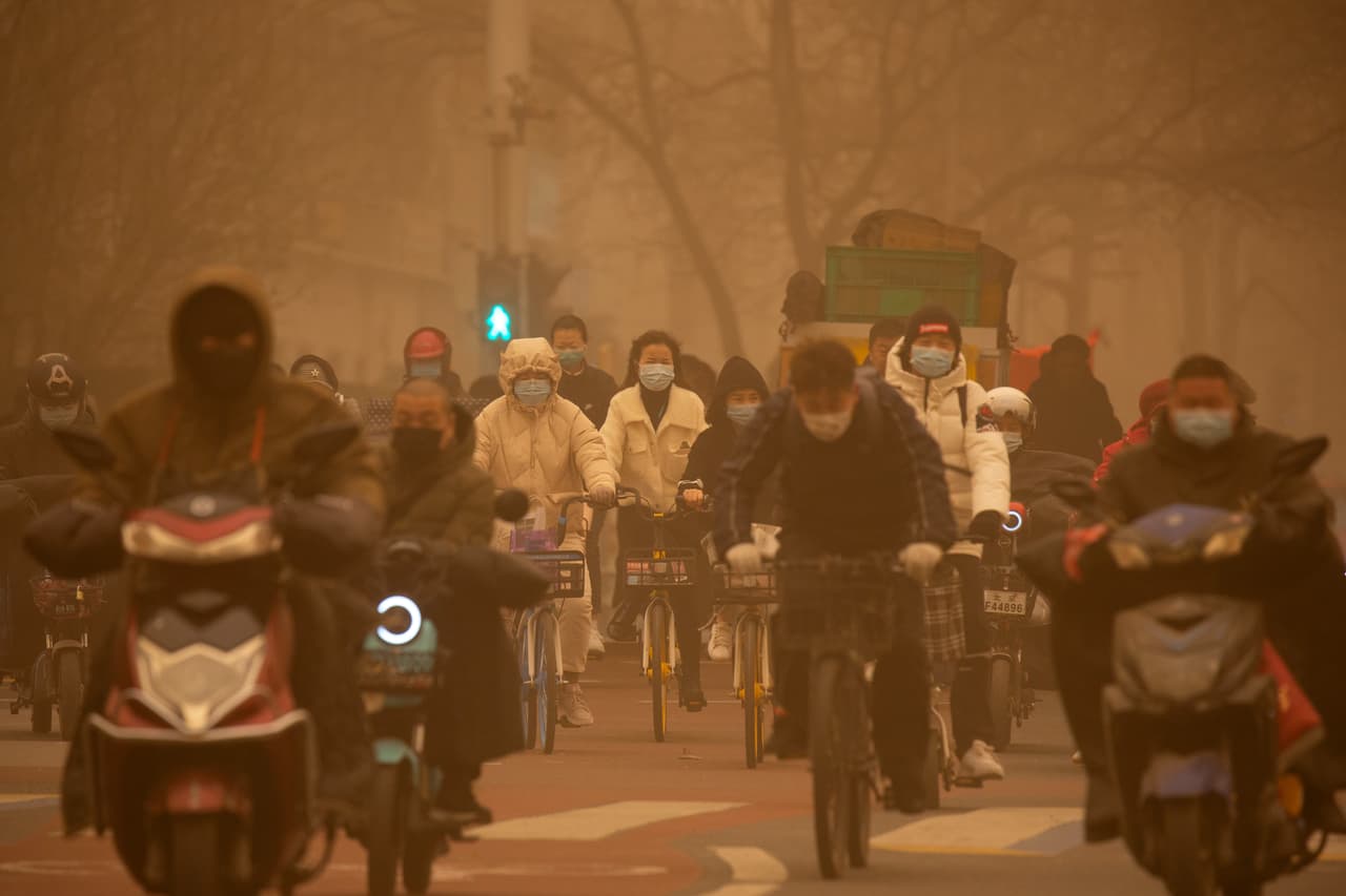 Transeuntes caminando dentro de la nube de arena que cubrió Beijing. La tormenta de arena, la más fuerte en los últimos 10 años, se formó en el Desierto de Gobi, en la región de Mongolia Interior, según el Centro Nacional de Meteorología de China.