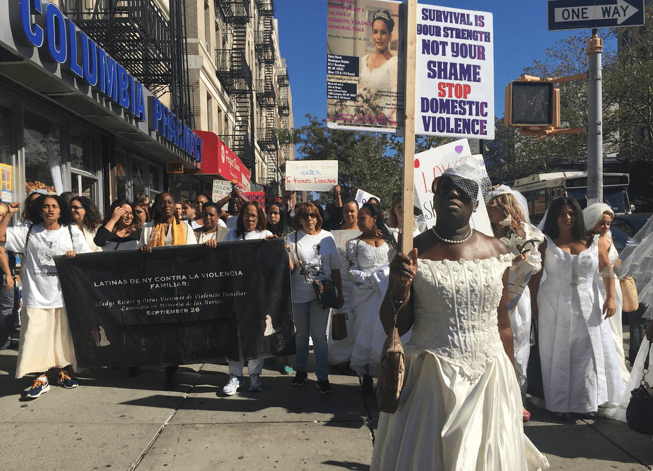 Allison Jones, en primer plano, carga el mensaje: "Sobrevivir es tu fortaleza, no una vergüenza: detén la violencia doméstica".