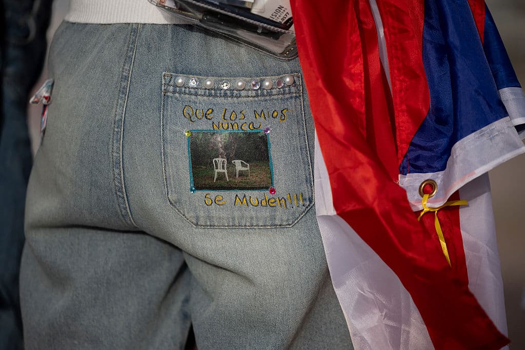 Algunas de las personas que han podido asistir a la residencia 'No me quiero ir de aquí', la serie de 30 conciertos que ofrece Bad Bunny en Puerto Rico, llevan 
<b>mensajes en sus vestimentas</b> como es este caso. Cita una frase del éxito 'Debí tirar más fotos', en la que expresa el deseo de cada boricua de que 
<b>su familia no tenga que dejar la isla en busca de calidad de vida</b>.
<br>Mientras 
<b>el gobierno resuelve</b>, Bad Bunny entretiene. Y ahora con 
<b><a href="https://www.univision.com/famosos/jennifer-lopez-formula-1-atuendo-rosa" target="_blank">la velocidad de la Fórmula 1</a></b>.