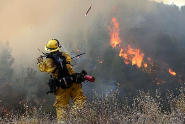 Un bombero lanza una bengala durante una operación.