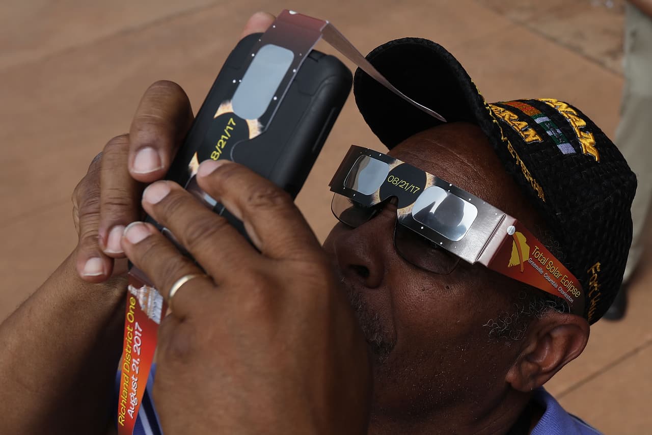 <b>Con doble lente:</b> En la búsqueda de la mejor fotografía, muchos utilizaron dos pares de lentes, unos para protegerse los ojos del sol y otros para filtrar mejor la luz en la cámara y captar en una imagen el eclipse. Chip Somodevilla/Getty Images