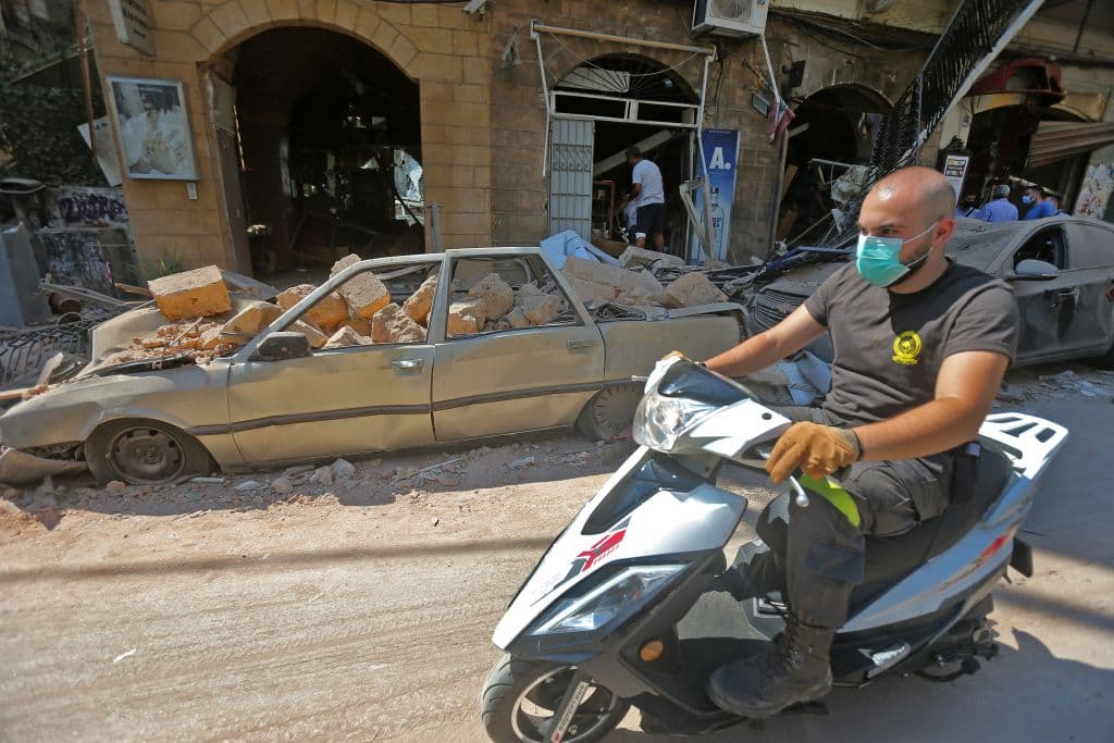 Un hombre con mascarilla pasa en moto por una calle claramente castigada por la gigantesca explosión que tuvo lugar en el puerto de Beirut.