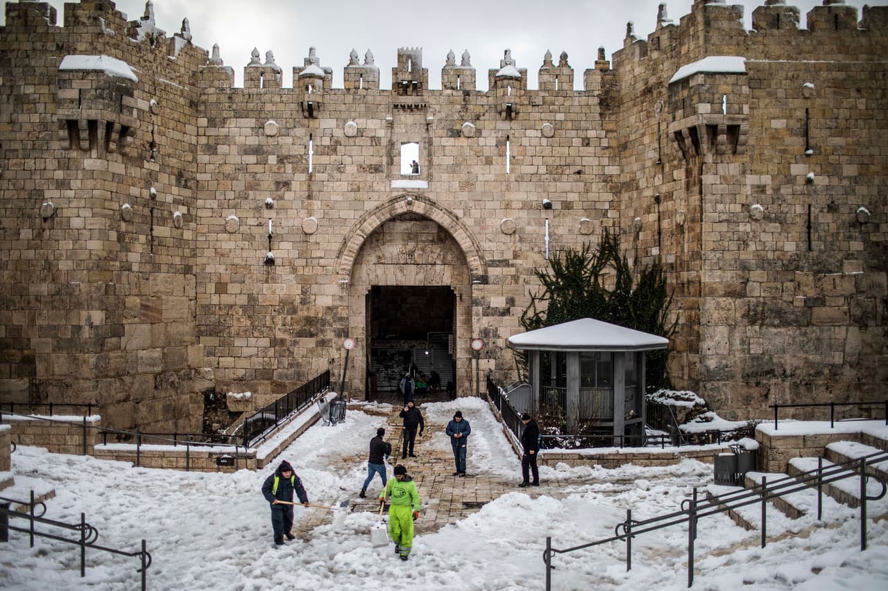 En la Cisjordania ocupada, también teñida de blanco en algunas partes, la Autoridad Palestina anunció el cierre de escuelas y de algunos servicios para evitar accidentes viarios. En la fotografía, trabajadores limpiando la nieve frente a la Puerta de Damasco.