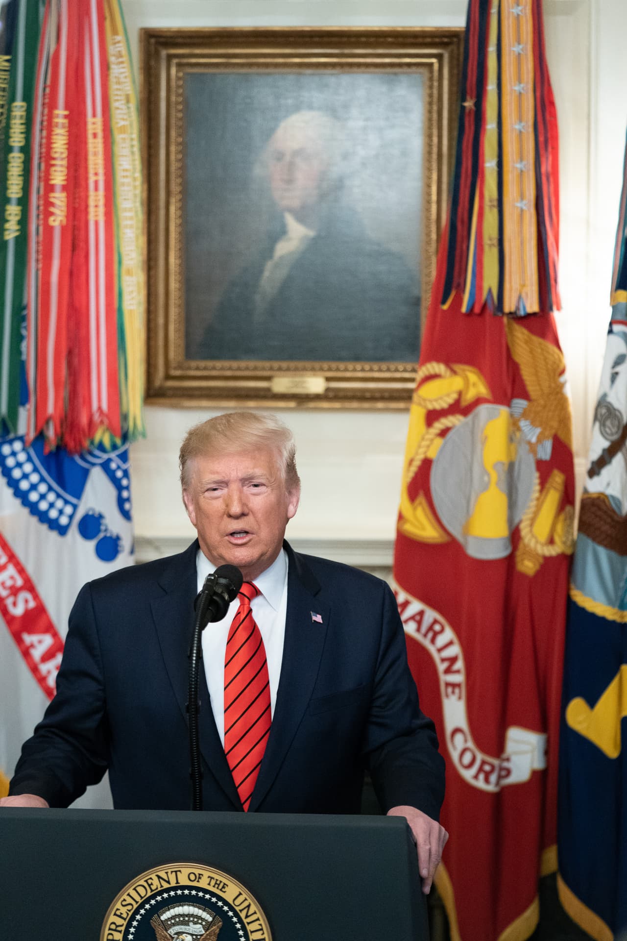 Detr´ás del presidente el retrato de George Washington.