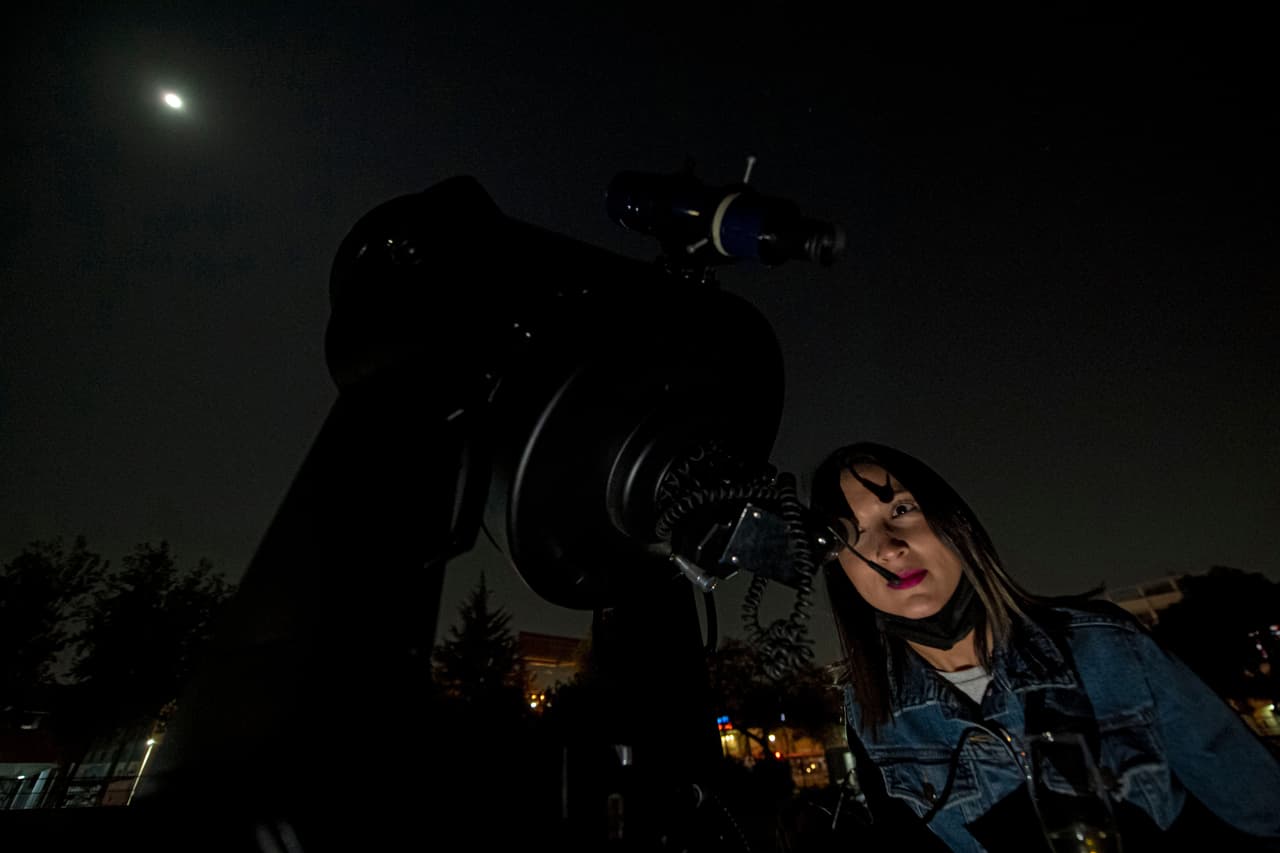 Una mujer mira a través deun telescopio el eclipse lunar en Santiago, Chile.