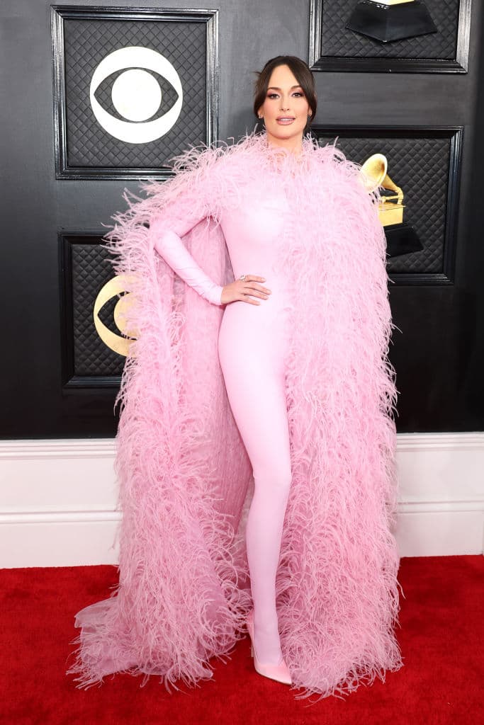 <h2 class="cms-H2-H2">Kacey Musgraves</h2>
<br>La cantautora de música country resaltó su escultural figura con un enterizo en color rosa. El toque glamuroso se lo dio la larga capa de finas plumas, perfecta para una noche tan especial.