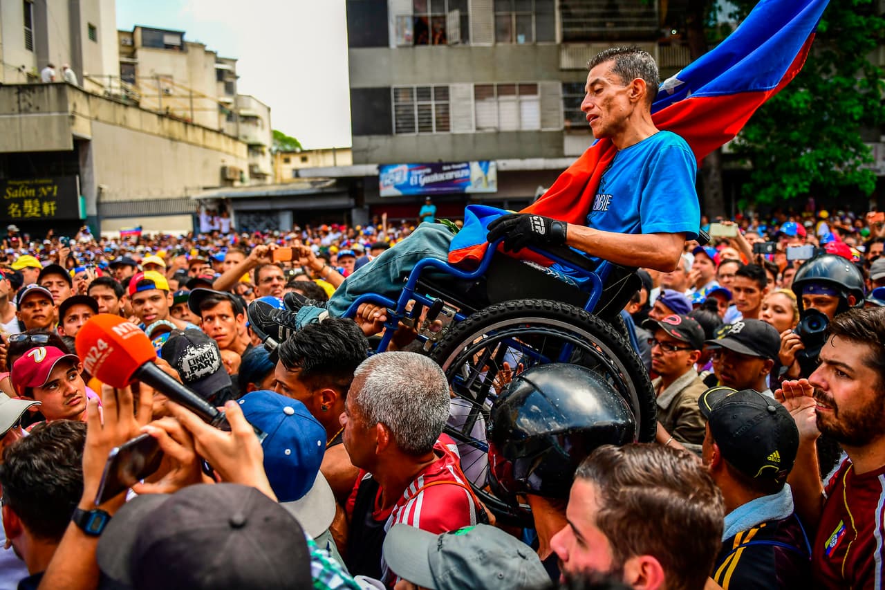 Manifestantes transportan a un hombre en silla de ruedas durante una protesta en Caracas.