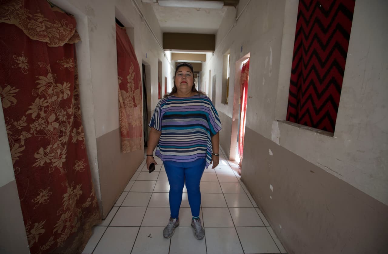 <b>Isabel Romero, Mexicali.</b> Isabel Romero es la directora del albergue gestionado por la organización Ángeles sin Fronteras que ha llegado a tener hasta 700 personas. “Duermen en los pasillos, en la azotea, en la parte de abajo”, dice. Romero cuenta cómo consiguieron rehabilitar el hotel en ruinas con apoyo del gobierno. Ahora, a pesar de los esfuerzos, el edificio está en malas condiciones: cortinas y cobijas hacen de puertas y ventanas y carece de ventilación para sobrellevar los sofocantes veranos.
<br>
<br>