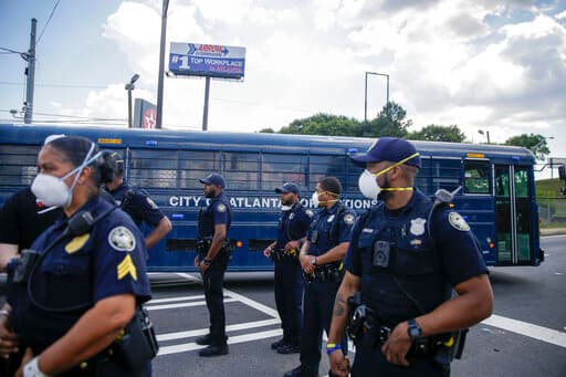 El sábado 13 de junio de 2020, cerca de Wendy's, donde la policía disparó y mató a Rayshard Brooks el viernes por la noche tras una lucha en la línea de autoservicio del restaurante, en Atlanta, los agentes se pararon junto a un manifestante en el autobús correccional de la ciudad de Atlanta cerca de los manifestantes.