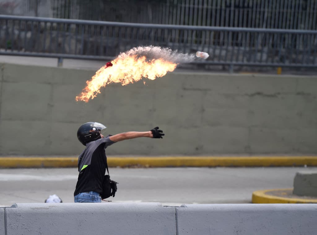 Un manifestante lanza una bomba molotov a la policía.