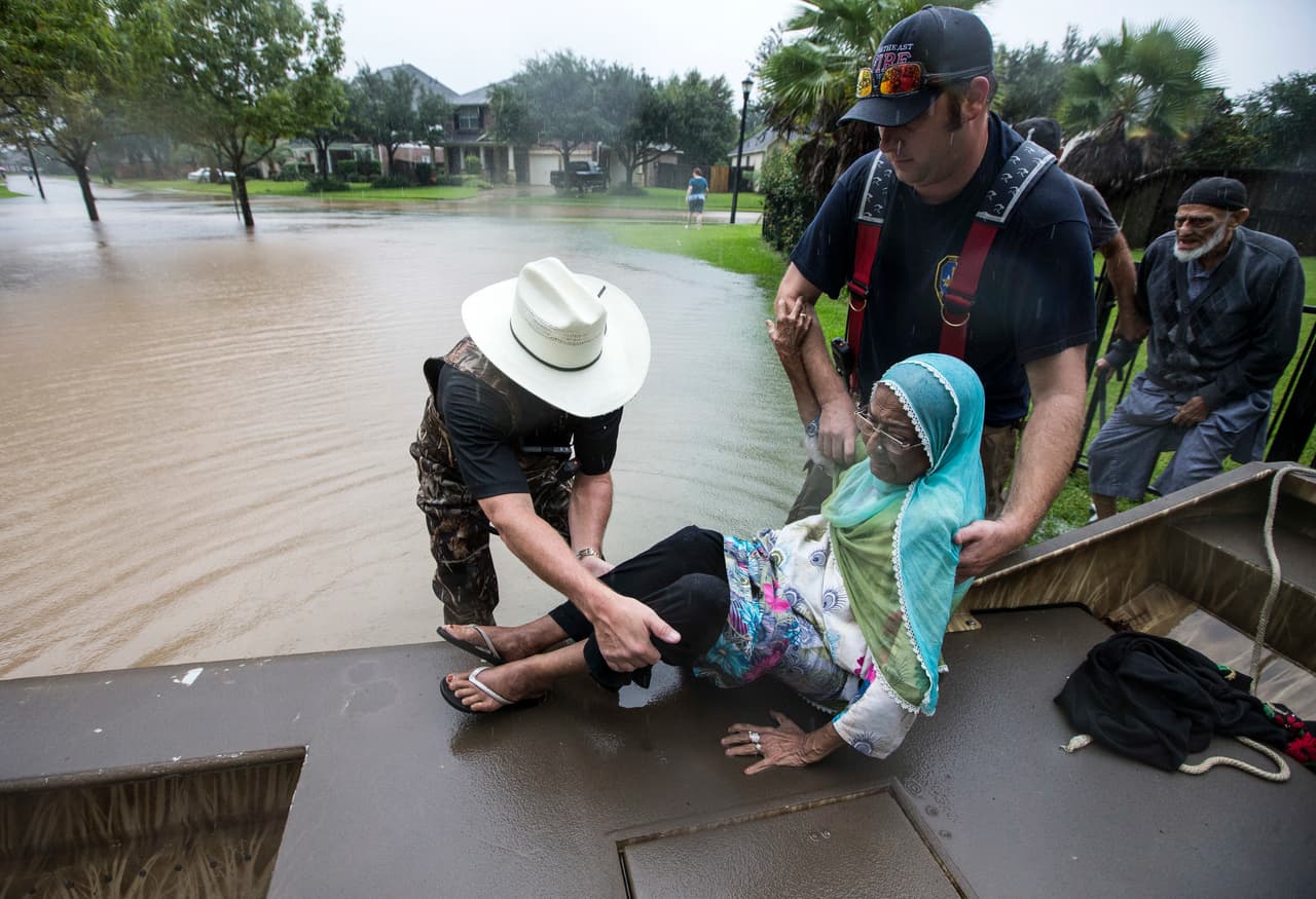 Troy Nehls, comisario del condado Fort Bend ayuda a Mumtaz Kara y a su esposo, quienes escapan de la inundación en Sugarland, al oeste de Houston.