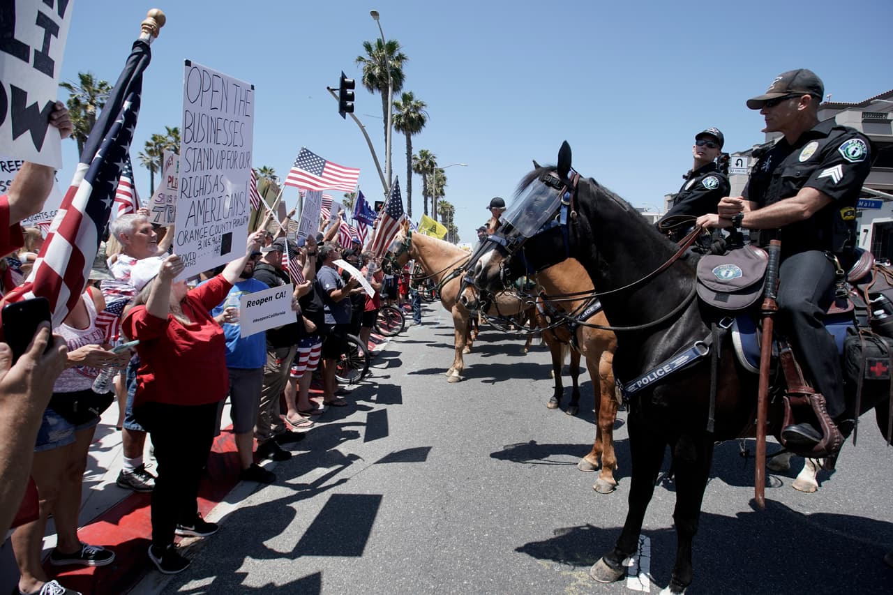 El primero de mayo se vieron varias protestas en todo California contra las medidas de los gobiernos estatales y locales que limitaron los negocios y ordenaron a las personas quedar en casa para contener el coronavirus. En Huntington Beach, se reunieron cientos de personas un día después de que el gobernador ordenara cerrar las playas del condado Orange. (AP Photo/Chris Carlson)