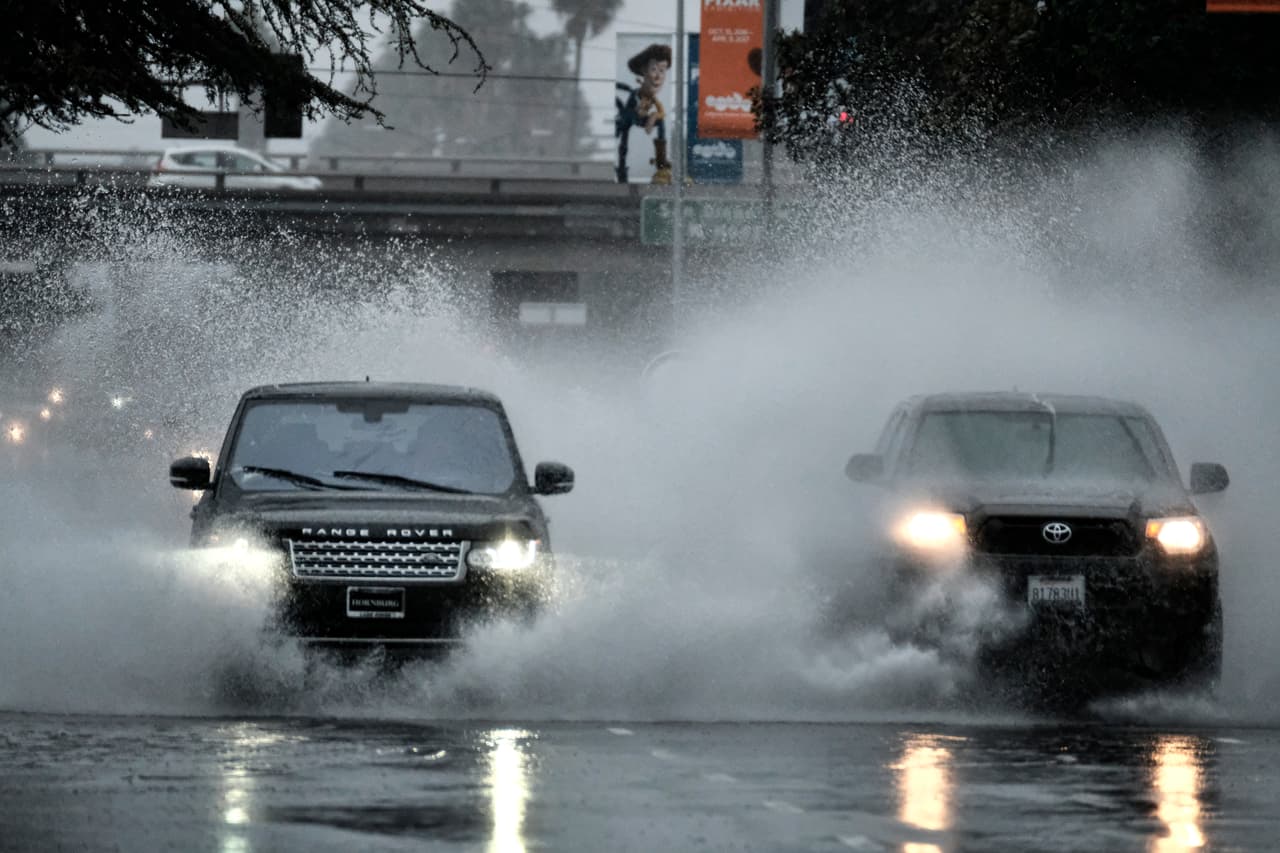 Los coches circulan a través de una calle inundada en la sección de Van Nuys de Los Ángeles.