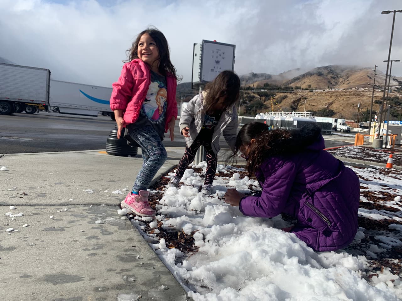 Los niños aprovechan de jugar con la nieve que cayó al lado de la carretera en Lebec.