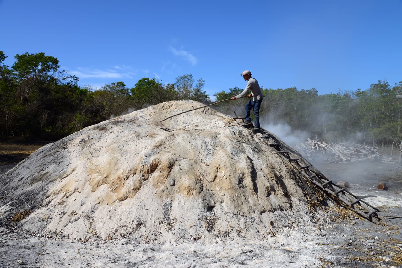 Matanzas Province, Cuba - March 5 2013: a charcoal maker at work on top of the burning mound of wood covered in ash, in the Matanzas Province of Cuba