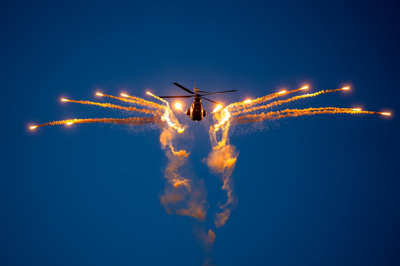 Un helicóptero militar dispara bengalas durante el Show Aeronáutico Internacional BIAS