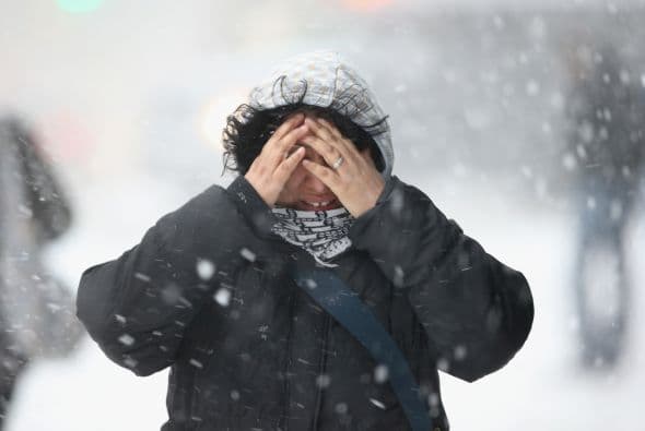 Una mujer se cubre el rostro en Nueva York mientras ca mina por una calle en Nueva York. Las autoridades advirten que la tormenta dejará al menos 38 centímetros de nieve.