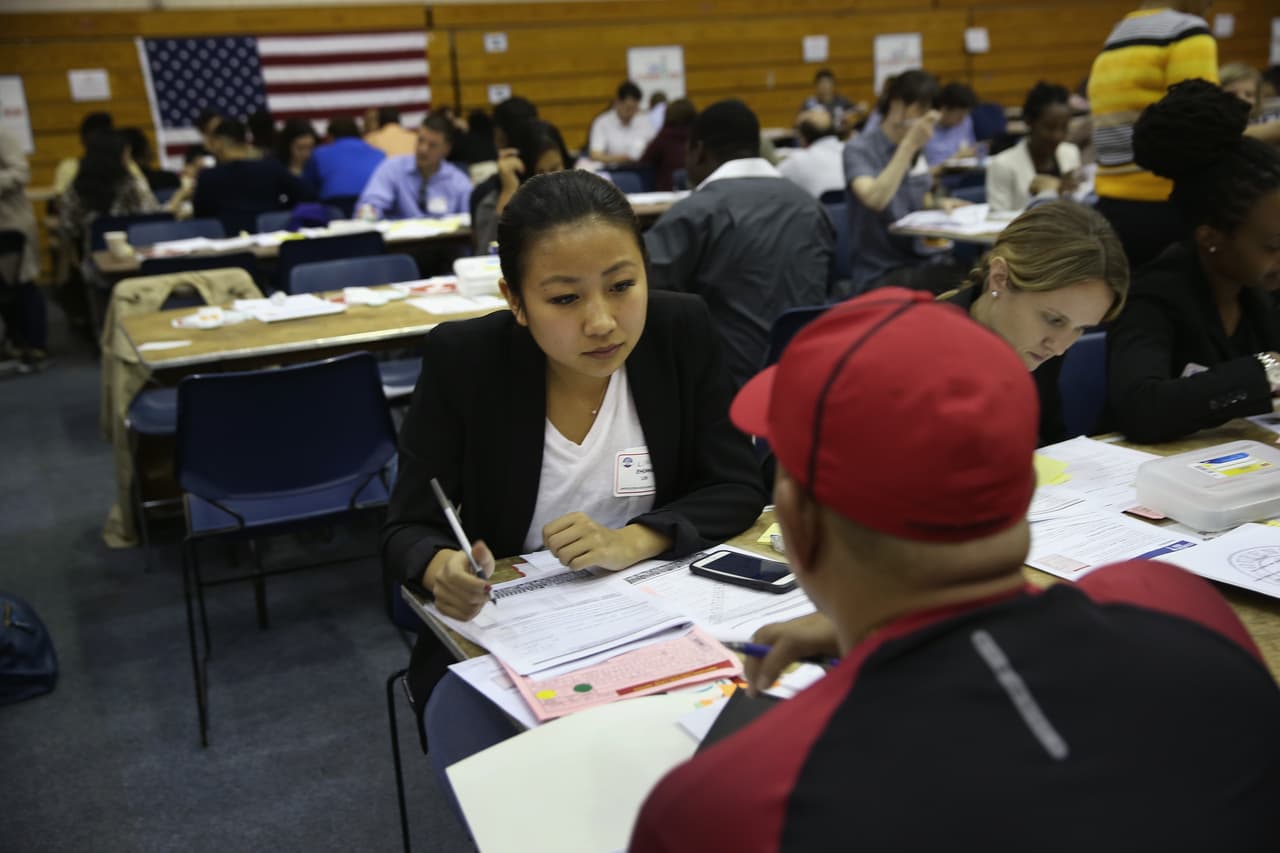 Una voluntaria asiste atentamente a un inmigrante con papeleo e información para la solicitud de la ciudadanía estadounidense.