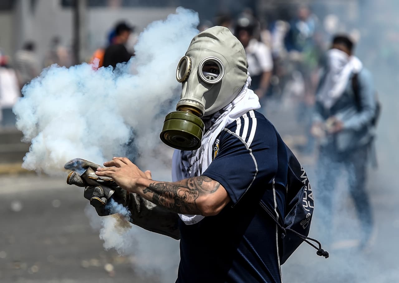 This protester is about to hurl a live tear gas round at police.
<br>