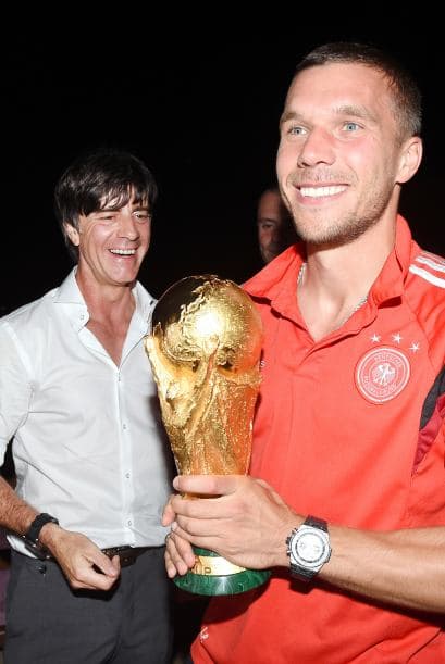 El técnico Joachim Löw junto a Lukas Podolski con el trofeo.