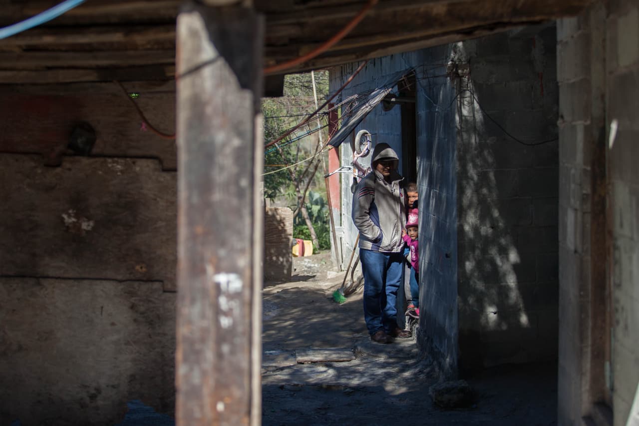 Carlos y sus hijos miran a la cámara desde la entrada de su casa.