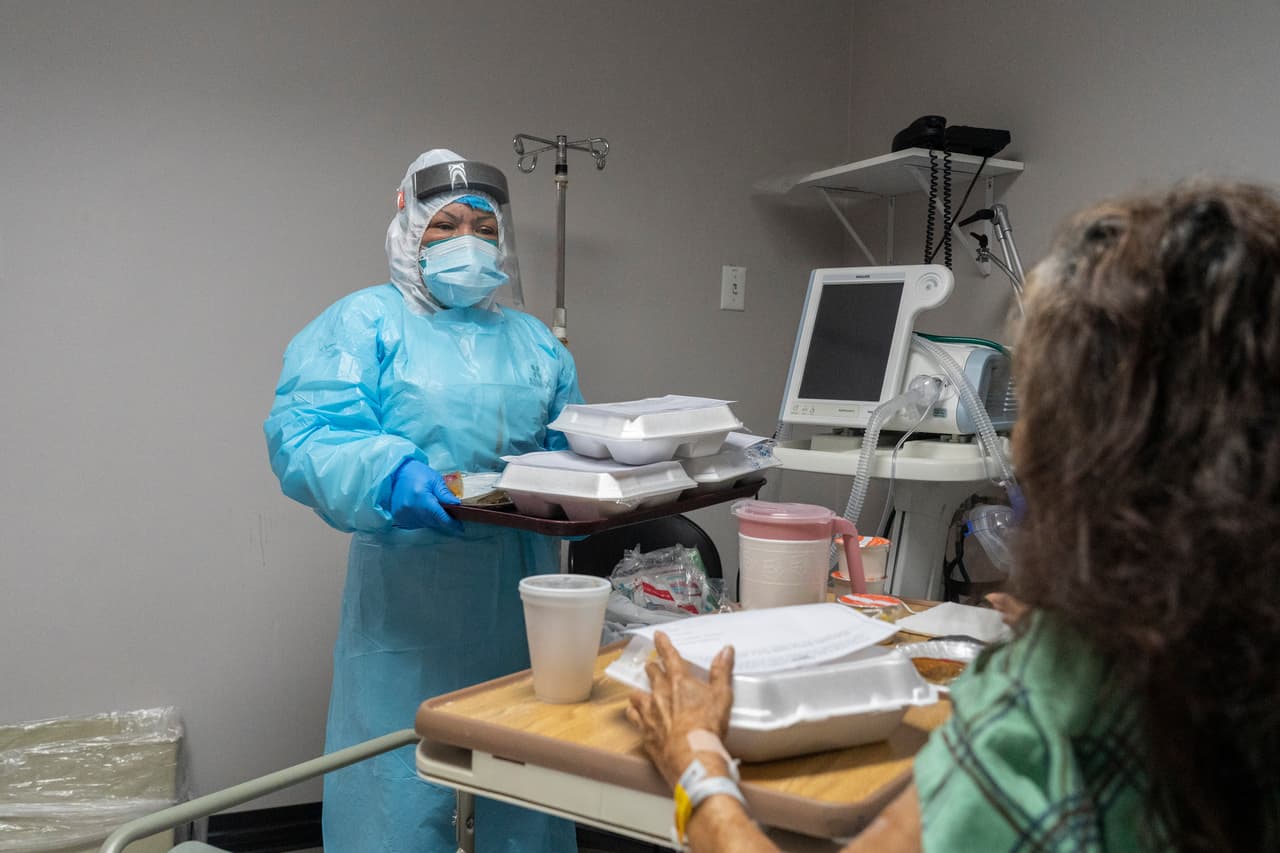 Un miembro del personal médico sirve comidas a un paciente en la unidad de cuidados intensivos (UCI) COVID-19 durante el Día de Acción de Gracias.