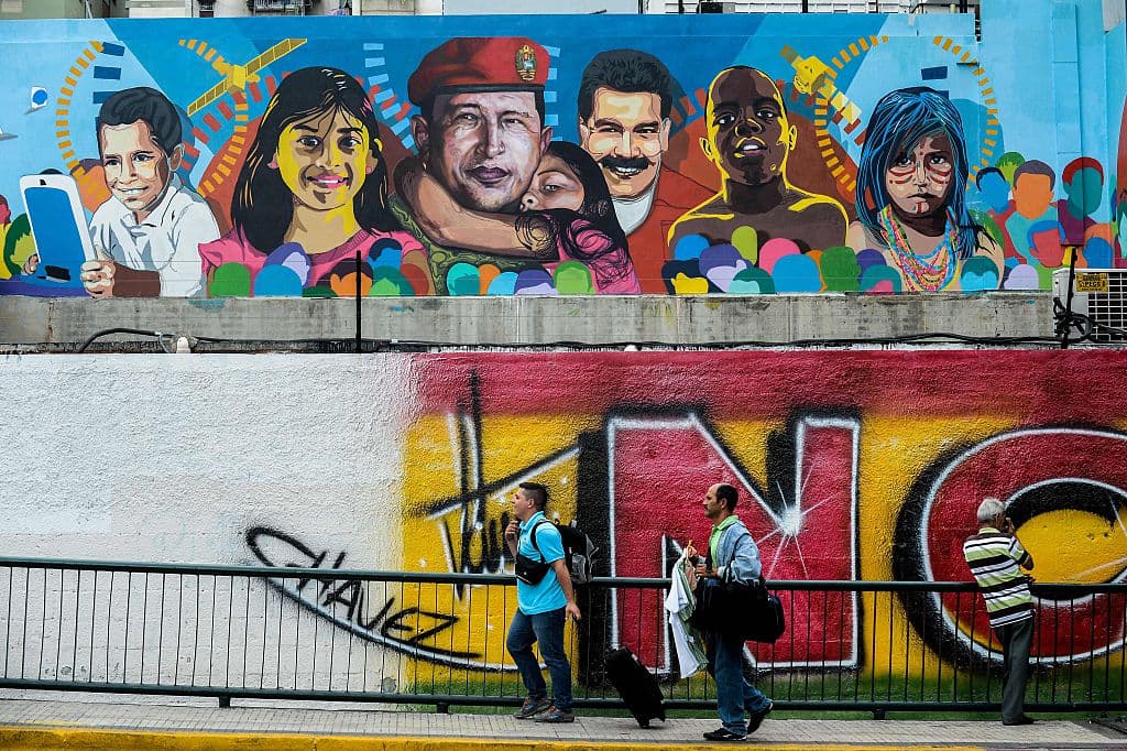 Pedestrians pass by a propaganda graffiti showing late Venezuelan President (1999-2013) Hugo Chavez (C) and Venezuelan President Nicolas Maduro (3-R) in Petare shantytown, Caracas on November 4 , 2015. About 35% to 40% of Venezuelans are "independent" but not necessarily apathetic, according to the polling firm Datanalisis. AFP PHOTO/FEDERICO PARRA / AFP / FEDERICO PARRA (Photo credit should read FEDERICO PARRA/AFP/Getty Images)