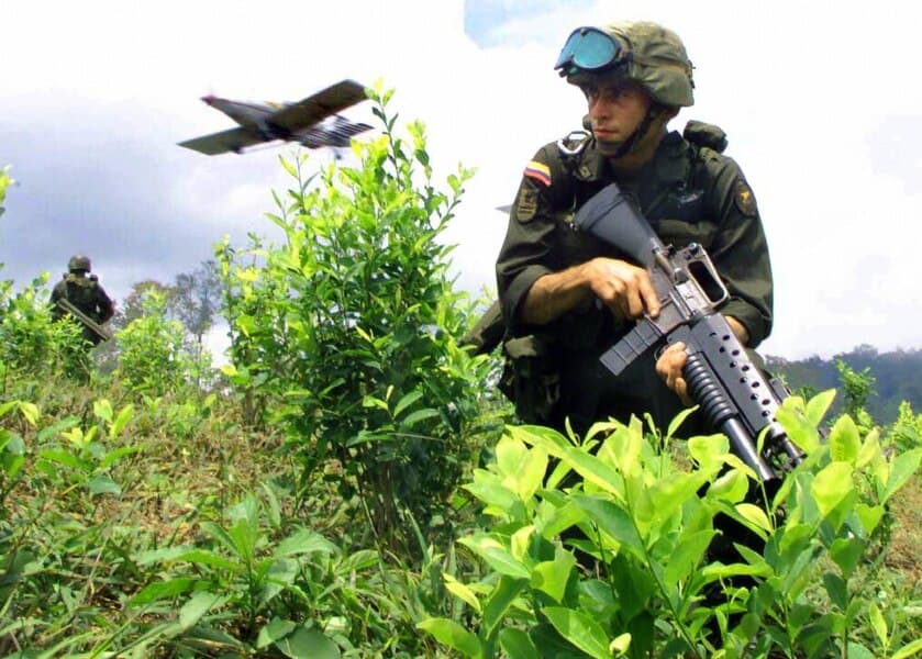 Un soldado colombiano en un campo de coca en Barbacoas, Colombia, mientras un avión fumiga con pesticidas.