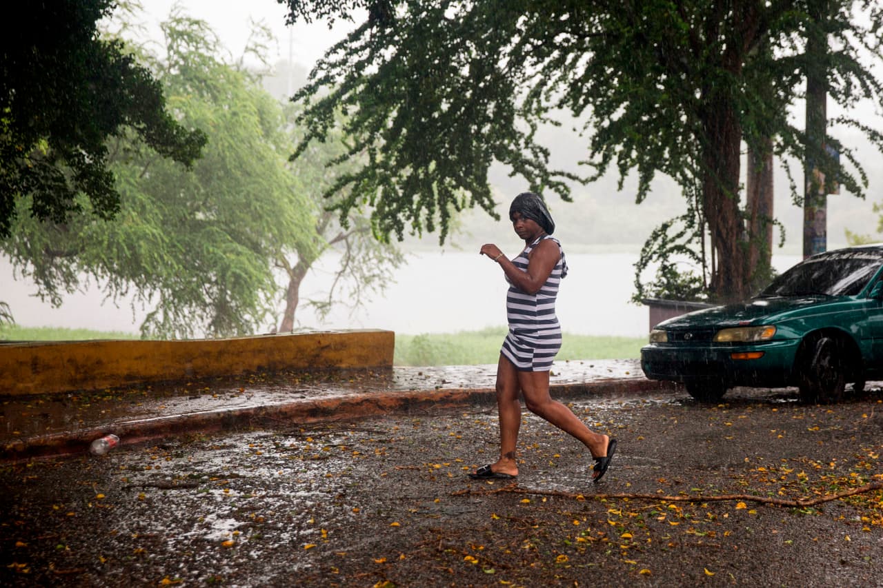 Una mujer camina bajo una lluvia torrencial durante la tormenta Isaías en Santo Domingo.