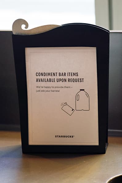 Un cambio que ya se había visto en muchos Starbucks es el limitar que los condimentos, como crema y azúcar, se ofrezcan solo al pedírselo a los empleados, para así evitar que los clientes toquen los frascos y jarras. (Cindy Ord/Getty Images)