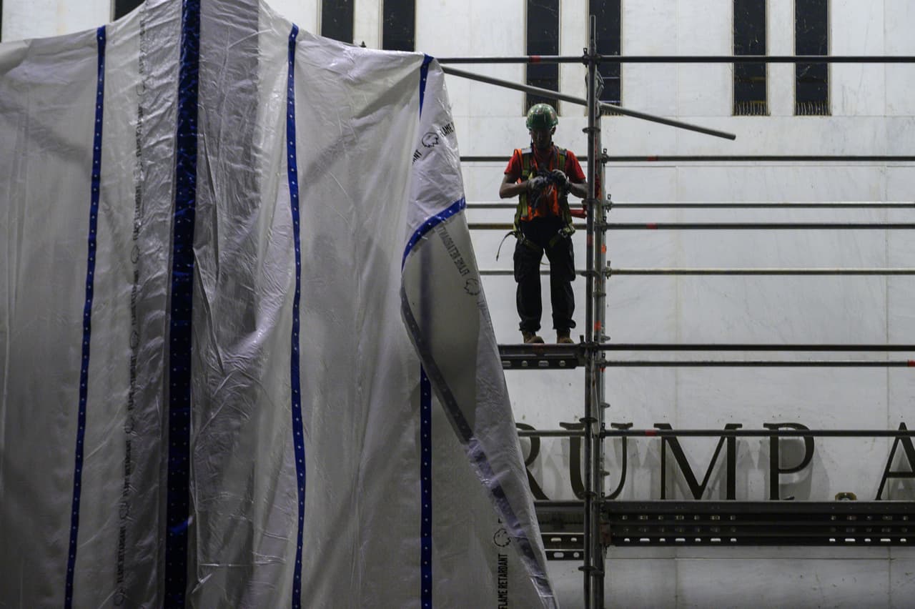 Trabajadores instalan lonas en los andamios del Centro John F. Kennedy este sábado 13 de junio.