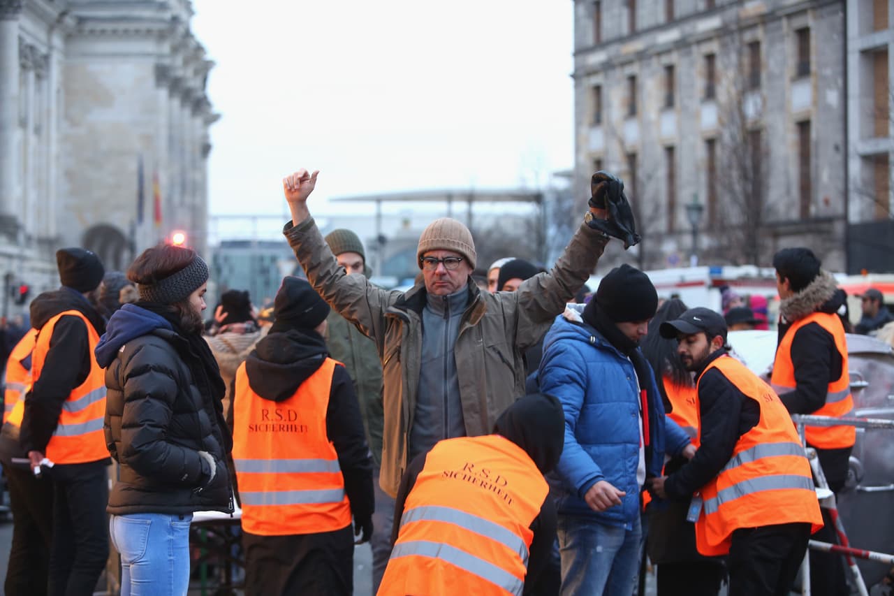 Los oficiales de seguridad inspeccionan bolsillos y la ropa de las personas que participan en los festejos de Año Nuevo en la Puerta de Brandenburgo en Berlín, Alemania.