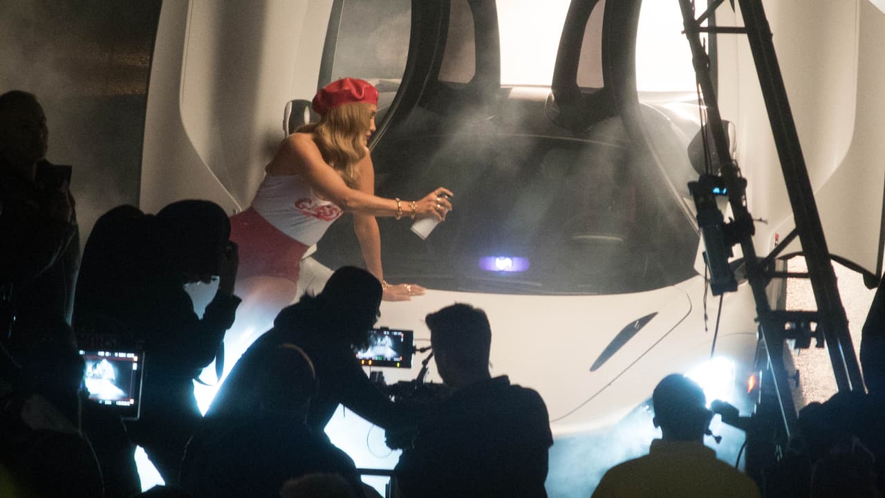 Jennifer López simula rociar pintura en aerosol sobre el parabrisas del McLaren 720S, el cual permanece con sus puertas abiertas en todo su esplendor.