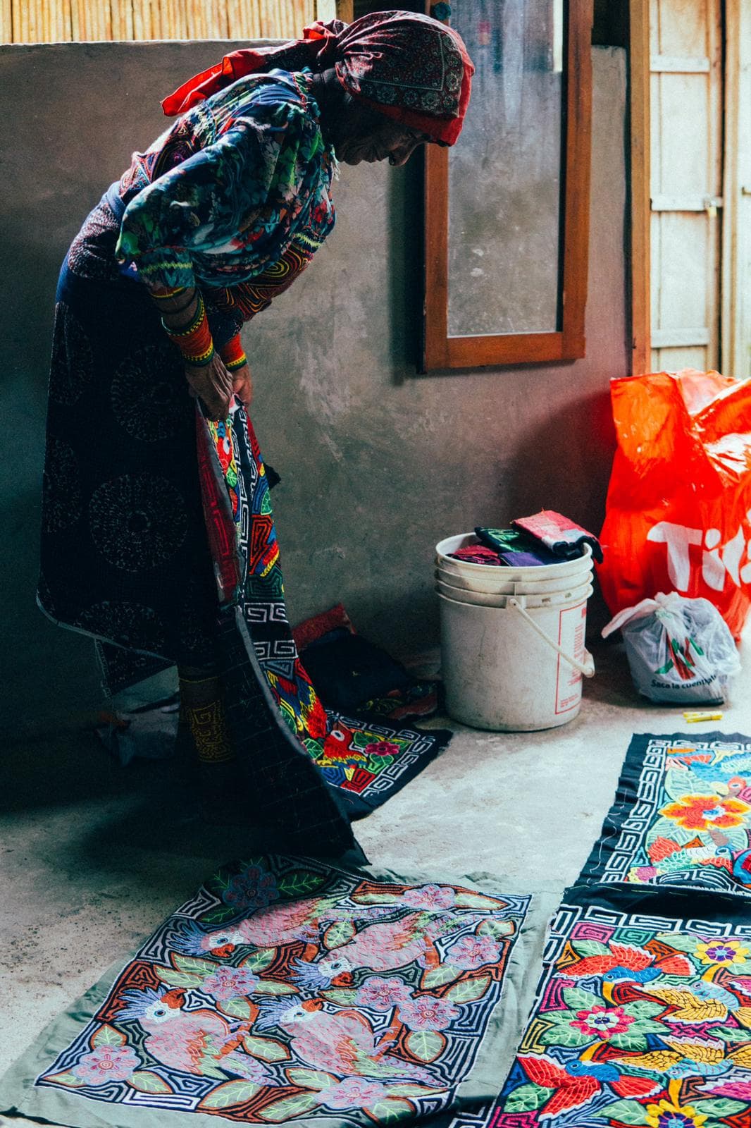 Una mujer Guna mostrando ejemplos de sus diseños coloridos de ropa tradicional, conocidos como 'mola'. La historia del pueblo Guna se remonta a unos 500 años atrás, a sus inicios a lo largo del río Darién, en una región muy remota de Panamá. Emigraron a las islas hace unos 150 años por la malaria y otras enfermedades tropicales, así como el impacto de la colonización de los descendientes de los exploradores españoles que llegaron en el siglo XV. 
<br>En 1938 los kunas alcanzaron la autonomía política, social y cultural en Panamá.