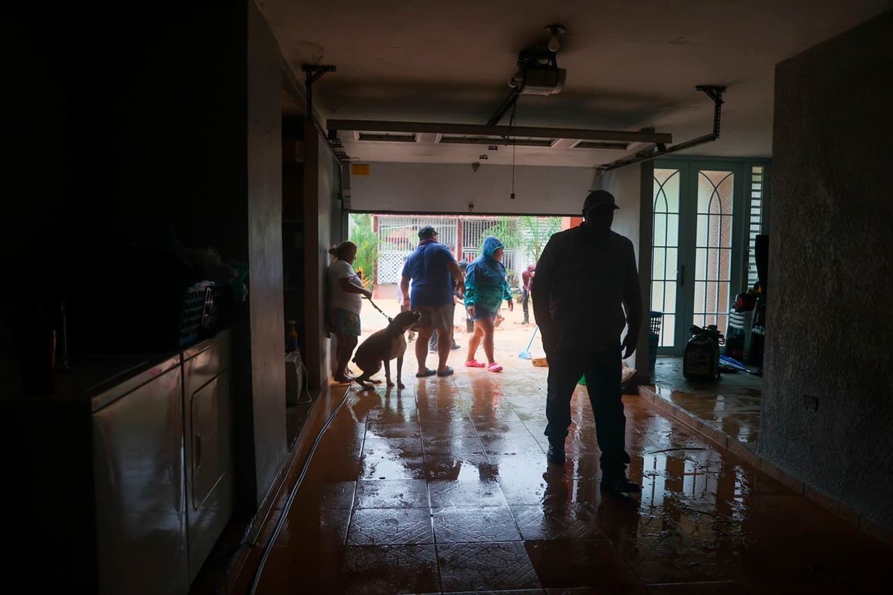 Los meteorólogos dijeron que la tormenta causaría inundaciones masivas y amenazó con arrojar niveles "históricos" de lluvia, con hasta 30 pulgadas (76 centímetros) posibles en el este y sur de Puerto Rico. En la foto, un grupo de personas limpian una casa inundada.